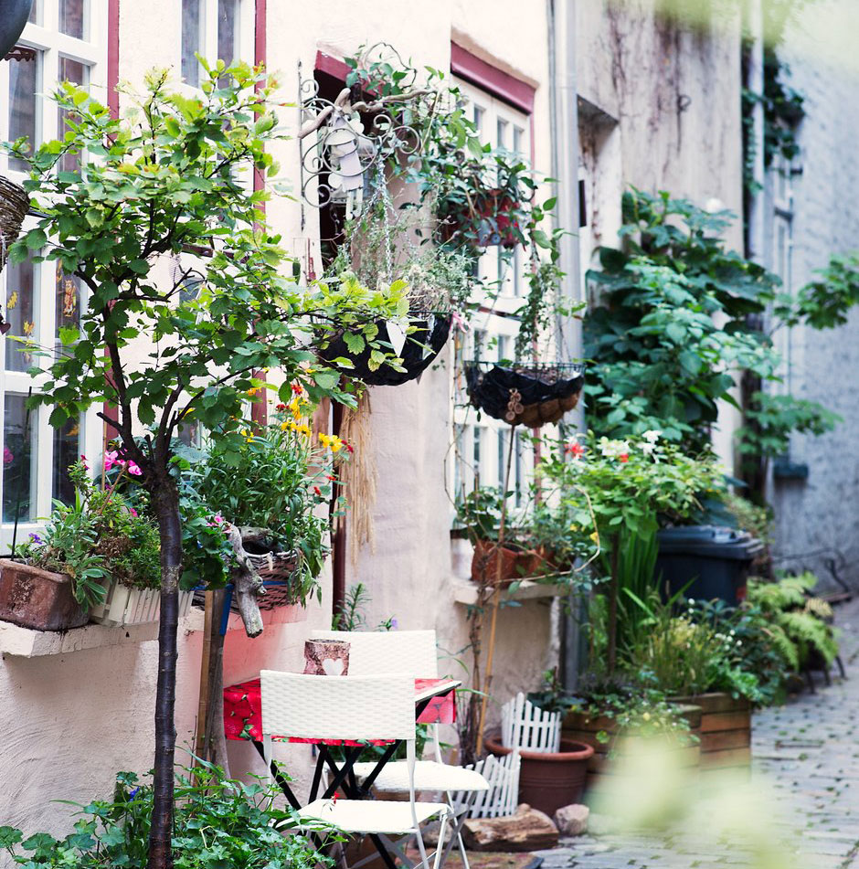 Ein Haus in der Lübecker Altstadt. Davor Blumentöpfe und eine Ampel sowie ein Tisch mit zwei Stühlen zum Verweilen.