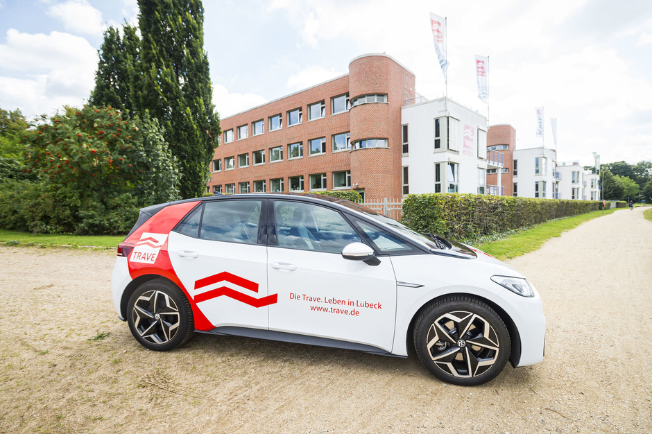 Elektrofahrzeug im TRAVE-Design vor dem Unternehmenssitz in der Falkenstraße 10 – Blick von der Wasserseite.