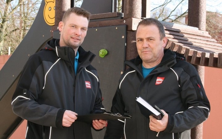 Zwei Hauswarte der TRAVE bei der Verkehrssicherung auf einem Spielplatz.